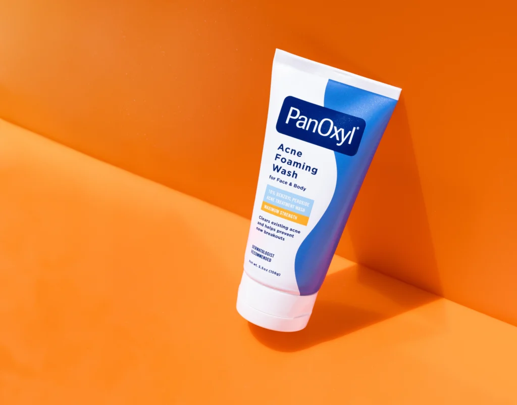 A tube of PanOxyl Acne foaming wash on an orange background