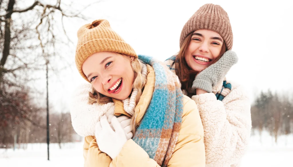 2 women in winter clothes smiling.