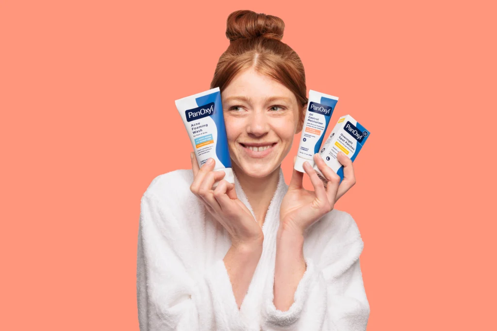 Woman Holding PanOxyl Control Moisturizer and Acne Foaming Wash Tubes.