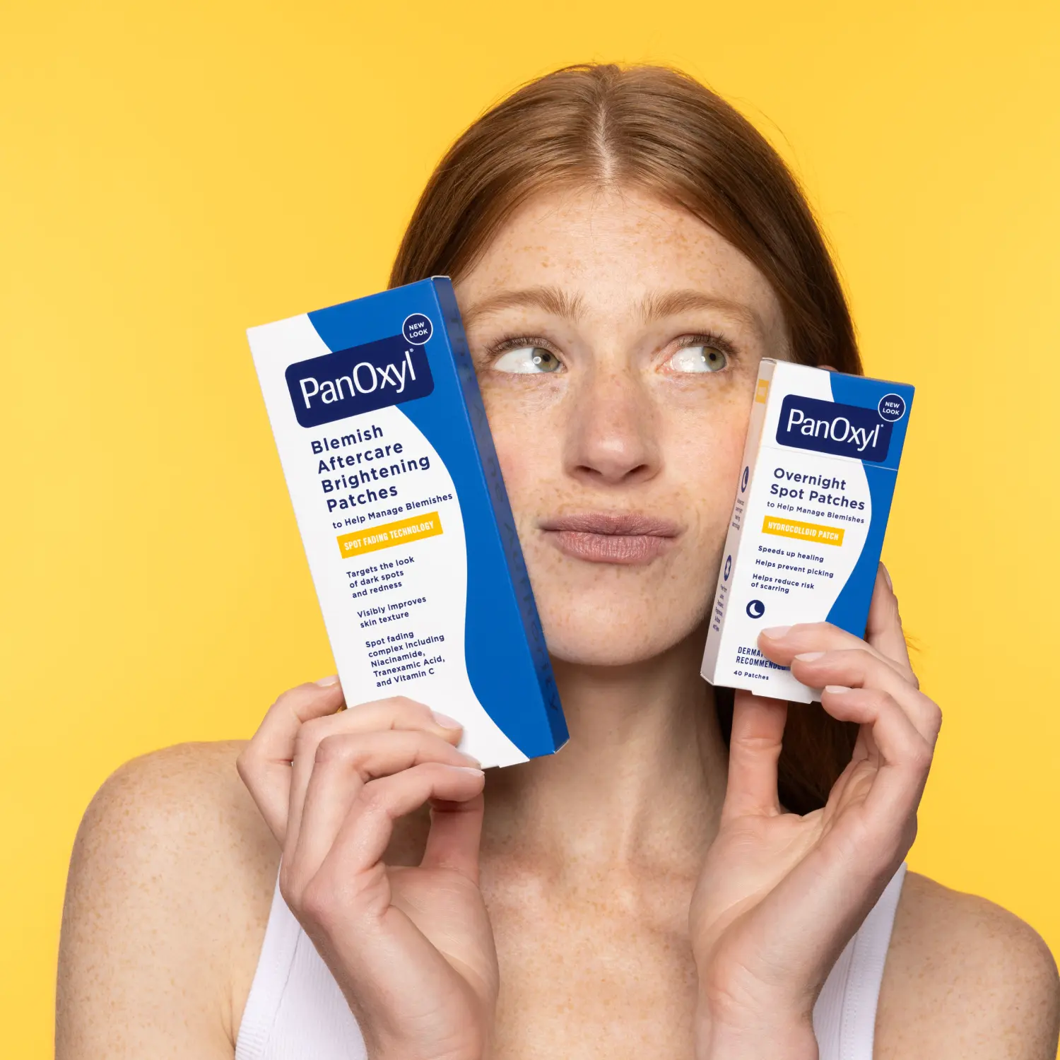 A person holding 2 different sizes boxes of PanOxyl Overnight Spot Patches