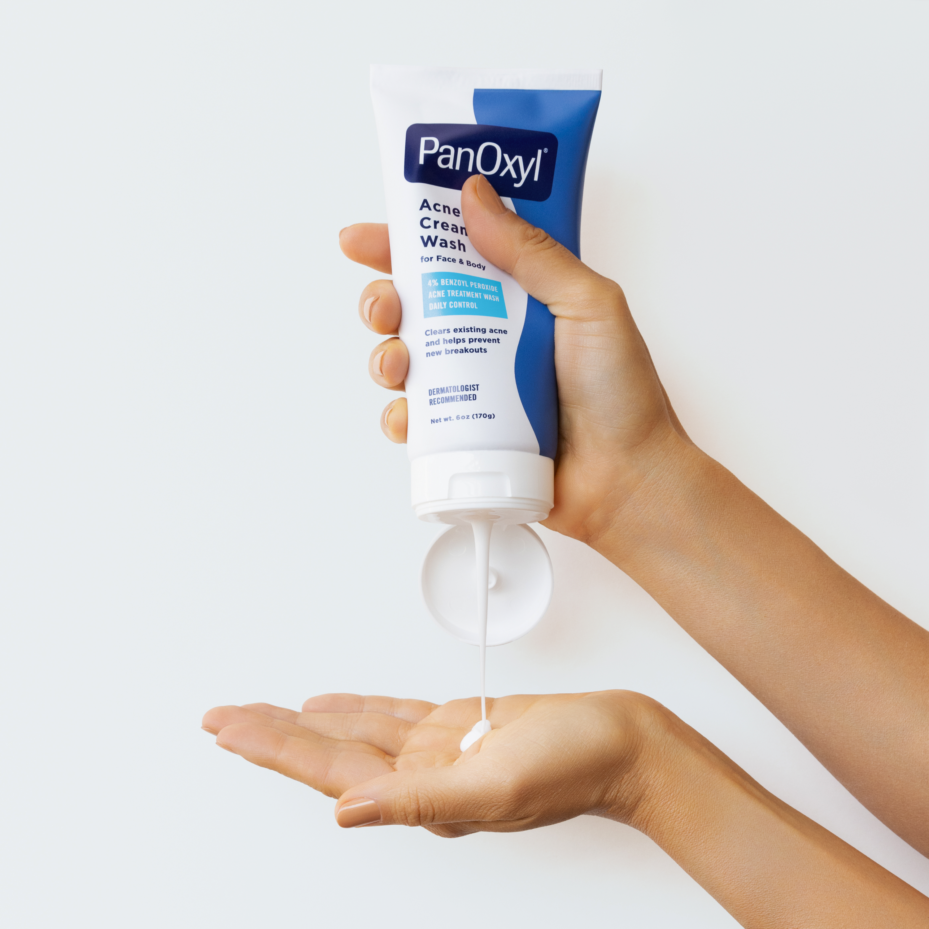 A hand squeezing PanOxyl Acne Creamy Wash on another hand