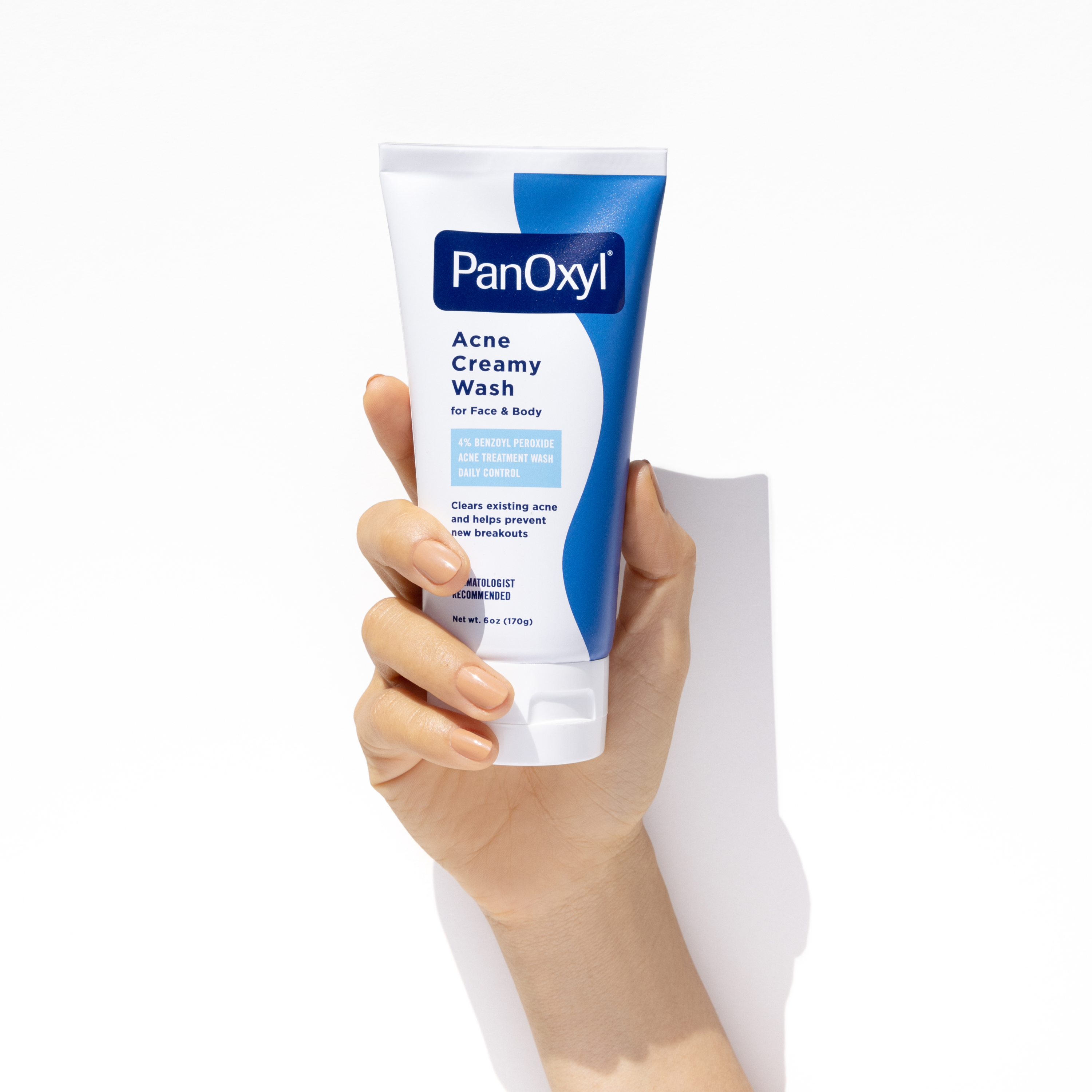 Hand holding PanOxyl Acne Creamy Wash on a white background