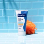 Thumbnail of A tube of PanOxyl Acne Foaming Wash on a blue tiled background with an orange loofah next to it