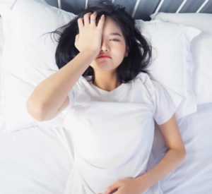 Woman lying in bed with her hand pressed against her face