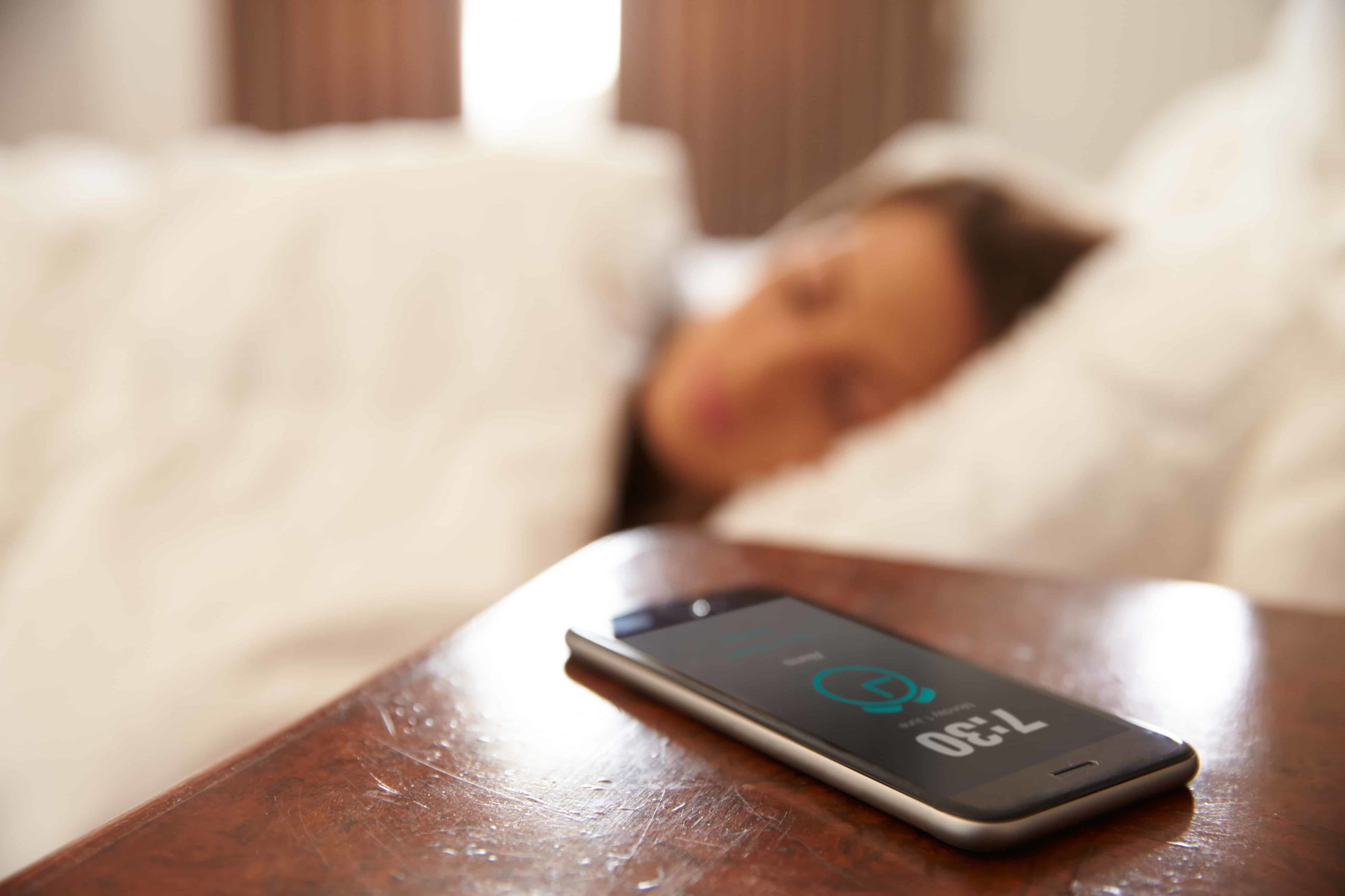 Cell phone alarm is going off while woman is in bed asleep