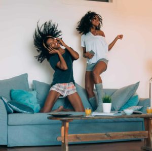 Two women dancing on a blue couch