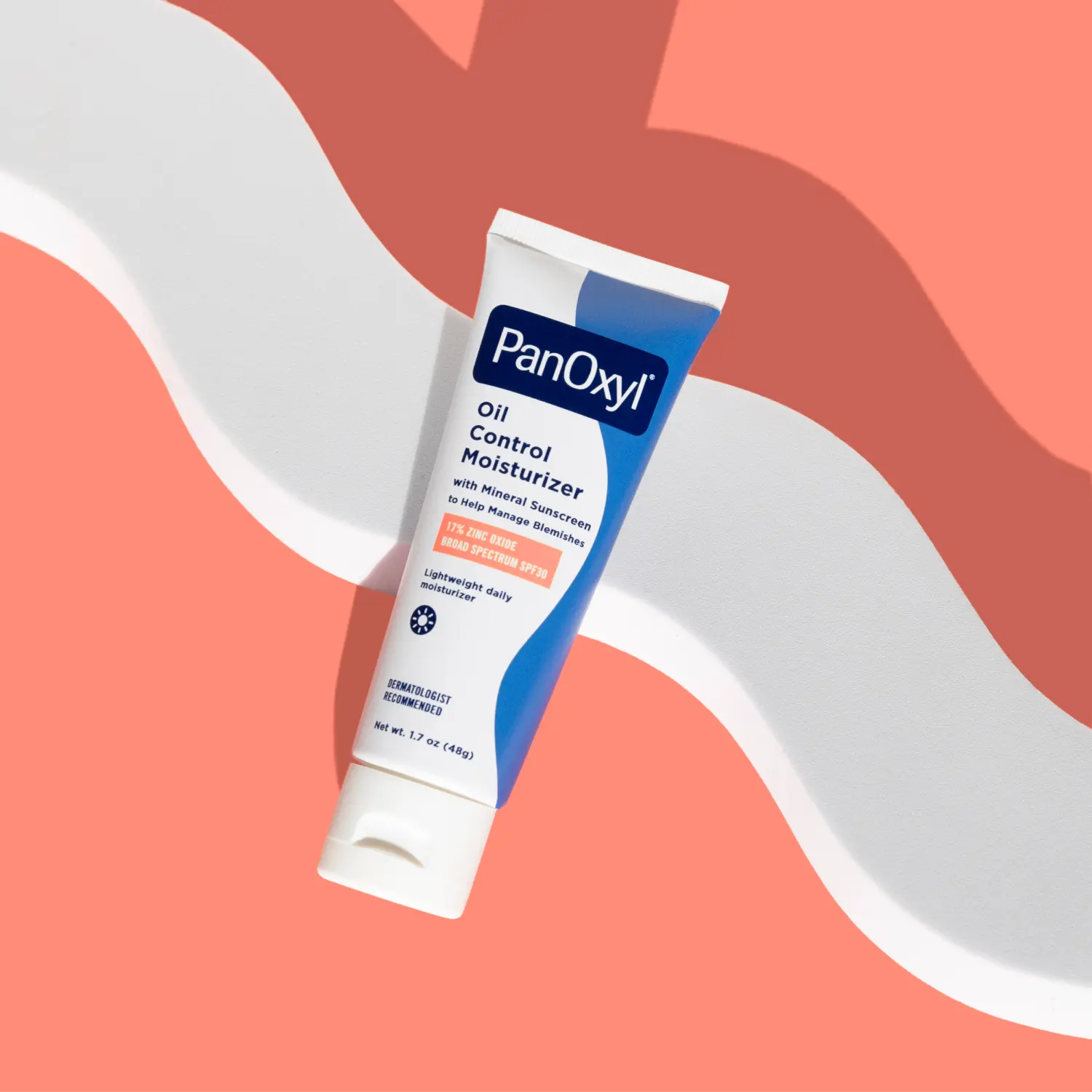 A tube of PanOxyl Oil Control Moisturizer on a coral background