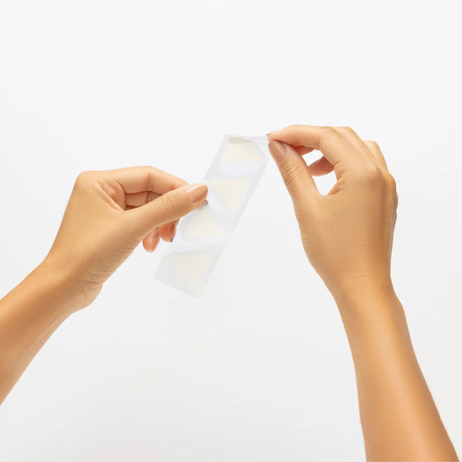 Hands holding a strip of PanOxyl Aftercare Brightening Patches