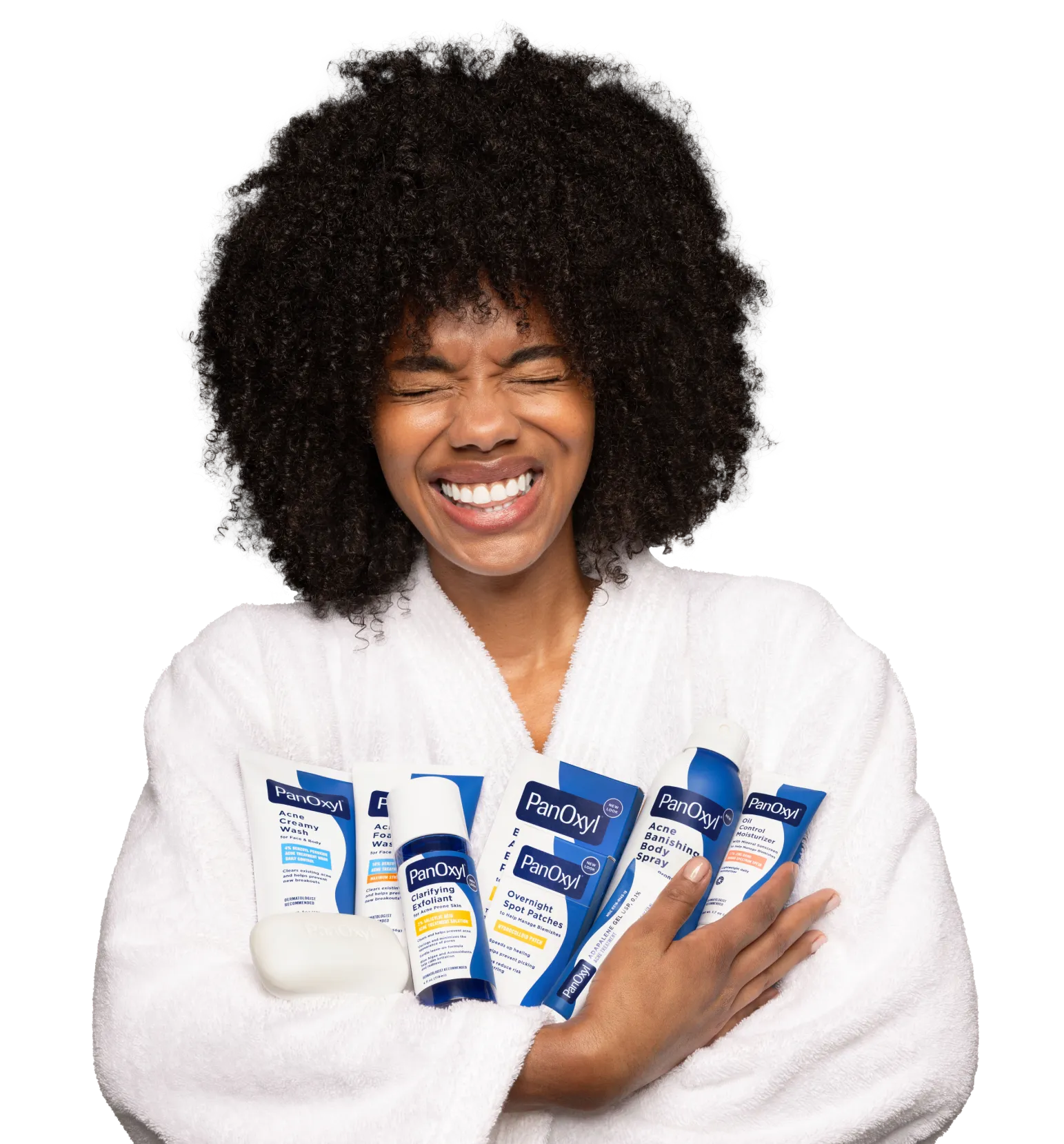 A woman in a white bathrobe smiling and holding all PanOxyl products.