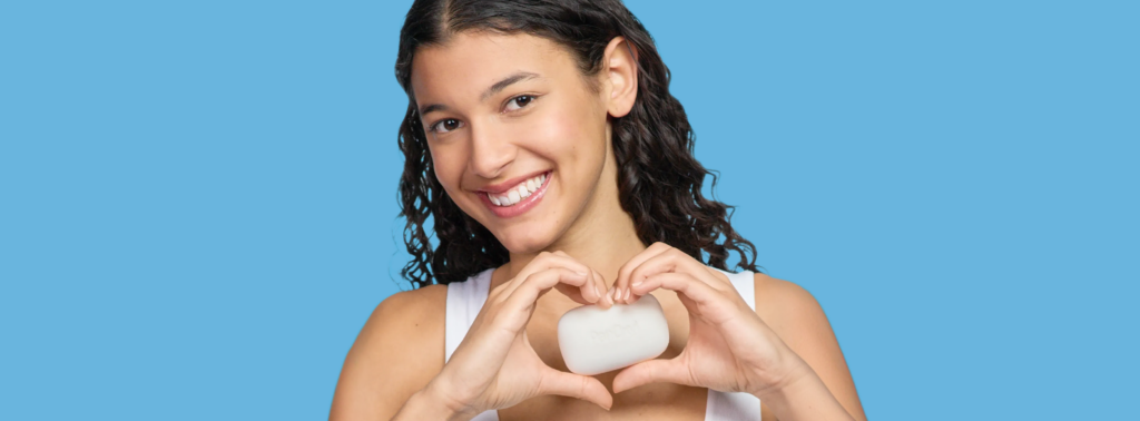 Smiling woman holding PanOxyl Acne Cleansing Bar on a blue background